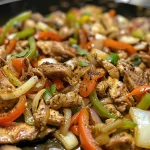 A vibrant Chicken Cheesesteak Skillet with sautéed vegetables and savory chicken, topped with gooey cheese.