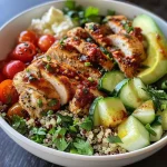 Colorful chicken quinoa bowl showcasing cucumber, parsley, and a drizzle of dressing.