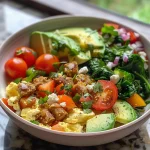 A side view of a Hearty Breakfast Scramble Bowl showcasing sausage, feta cheese, and fresh greens.