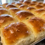 Freshly baked soft dinner rolls displayed on a wooden table.