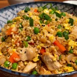 Juicy chicken fried rice served in a bowl, showcasing vibrant carrots and peas.