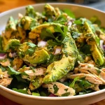 A detailed view of avocado chicken salad served in a bowl, highlighting the creamy texture and fresh herbs.