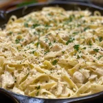 Side view of Chicken Alfredo pasta garnished with parsley and a rich sauce.