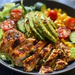 Juicy grilled chicken on a bed of lettuce, tomatoes, and cucumber, garnished with red pepper flakes.
