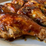 Side view of cooked BBQ chicken thighs, showcasing a rich glaze and succulent meat.