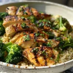 A colorful bowl filled with juicy grilled chicken, broccoli, and creamy sauce.