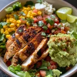 Vibrant chicken taco bowl featuring sliced avocado, black beans, corn, and cherry tomatoes.