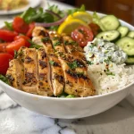Detailed shot of a Healthy Greek Chicken Bowl with vibrant greens and creamy tzatziki sauce.