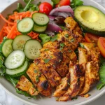 An appetizing presentation of Light Chicken Shawarma Salad showcasing marinated chicken over a bed of mixed greens and assorted vegetables.