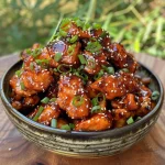 Delicious Sticky Honey Gochujang Chicken presented on a plate, showcasing its sticky glaze and fresh toppings.