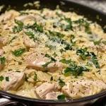 Side view of skillet chicken topped with a creamy lemon dill sauce.