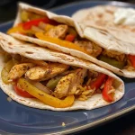 Detailed image of a Chicken Fajitas Wrap bursting with chicken, peppers, and creamy toppings.