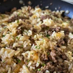 Close-up of a juicy beef onion rice skillet, showcasing glossy rice and caramelized onions.