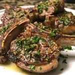 Juicy garlic herb lamb chops garnished with fresh herbs, captured from the side.