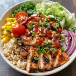 Detailed shot of a protein-packed chicken bowl loaded with diced onions, shredded cheese, and garnished with cilantro.