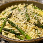 Close-up view of lemon Parmesan orzo garnished with fresh asparagus, featuring vibrant colors.