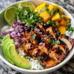 Close-up view of a BBQ Chicken Mango Bowl featuring chicken, mango, avocado, and rice.