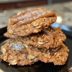 Close-up view of caramel oatmeal cookies with a golden-brown exterior and visible toffee bits.