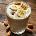 Creamy Banana Almond Smoothie in a glass, side view showcasing thick texture and banana slices.