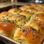 Close-up of golden-brown garlic herb pull-apart dinner rolls, glistening with brown butter.