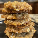 A close-up side view of golden Honey Oatmeal Cookies on a surface.