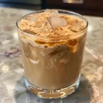 Close-up of a refreshing iced honey cinnamon latte with ice cubes and whipped cream.