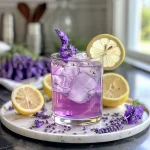 Close-up view of a glass of Lavender Lemonade with a vibrant purple hue and lemon slices.