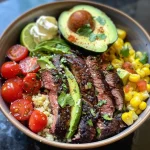 A close-up side view of a vibrant steak, avocado, and corn bowl topped with cilantro cream sauce.