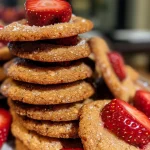 Close-up of a freshly baked strawberry cookie with visible fruit pieces.