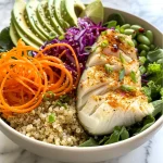 A vibrant Buddha bowl featuring quinoa, mixed greens, sliced avocado, and grilled white fish.