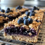 ['Close-up side view of gooey Blueberry Oatmeal Bars on a wooden surface.', 'Deliciously baked Blueberry Oatmeal Bars with visible blueberries, displayed on a white plate.', 'A side view of fresh Blueberry Oatmeal Bars, showcasing their texture and fruit filling.', 'Close-up of a slice of Blueberry Oatmeal Bars highlighting the blueberries and oatmeal layers.']