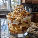 ['Close-up view of a caramel apple dessert cup with layers of apples, caramel, and crushed cookies.', 'Side view of a dessert cup filled with chopped apples, caramel drizzle, and whipped cream.', 'Delicious caramel apple dessert cup showcasing layers of ingredients, including apples and caramel sauce.', 'Detailed image of a dessert cup featuring caramelized apples and a creamy topping in a clear container.']