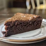 ['A side view of a moist chocolate protein cake showcasing a rich chocolate frosting.', 'Close-up of a chocolate protein cake with a glossy frosting, revealing its layered texture.', 'A slice of chocolate protein cake from the side, highlighting the fluffy interior and smooth chocolate covering.', 'Juicy chocolate protein cake displayed at an angle, accentuating its decadent appearance.']