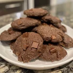 ['Close-up view of chewy chocolate protein cookies showing chocolate chunks.', 'Side view of delicious chocolate protein cookies with a rich texture.', 'Juicy chocolate protein cookies displayed on a surface, highlighting ingredients.', 'Close-up of moist chocolate protein cookies with a glossy finish.']