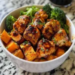 ['Close-up view of a Crispy Chicken and Roasted Sweet Potato Bowl with vibrant colors.', 'A side view of a bowl filled with crispy chicken, cubed sweet potatoes, and broccoli.', 'Detailed shot of a hearty bowl featuring roasted sweet potatoes and golden chicken pieces.', 'An appetizing image showcasing a chicken and sweet potato bowl garnished with yogurt.']