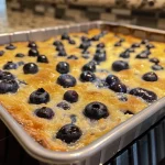 ['Close-up view of a slice of Greek Yogurt Bake topped with blueberries.', 'Side profile of a delicious Greek Yogurt Bake showcasing its fluffy texture.', 'Juicy Greek Yogurt Bake with visible blueberries and a golden-brown top.', 'A serving of Greek Yogurt Bake presented on a plate, garnished with lemon zest.']