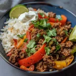 ['A close-up side view of a vibrant ground beef fajita bowl featuring colorful bell peppers, onions, and rice.', 'A delicious ground beef fajita bowl with diced vegetables, cilantro, and a lime wedge, presented elegantly.', 'Juicy ground beef fajita bowl filled with sliced bell peppers, onions, and topped with sour cream and cilantro.', 'A colorful and appetizing ground beef fajita bowl showcasing fresh ingredients and garnishes.']