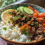 ['A close-up side view of ground beef shawarma rice with vibrant toppings.', 'Juicy ground beef shawarma served over rice, garnished with fresh vegetables.', 'A detailed shot showcasing ground beef shawarma rice with cucumber, tomatoes, and onion.', 'A colorful plate of ground beef shawarma rice, featuring sliced vegetables and aromatic spices.']