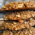 ['A close-up view of healthy peanut butter oatmeal cookies with a golden-brown exterior.', 'Side view of perfectly baked peanut butter oatmeal cookies, showing a chewy texture.', 'Juicy and delicious healthy oatmeal cookies with visible peanut pieces and a warm color.', 'A cluster of healthy peanut butter oatmeal cookies, highlighting their rustic appearance.']