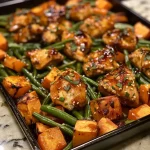['Close-up view of honey garlic chicken with sweet potatoes and green beans.', 'Succulent honey garlic chicken alongside cubed sweet potatoes and green beans.', 'Side view of a plated dish featuring honey garlic chicken, sweet potatoes, and green beans.', 'Detailed shot of honey garlic chicken served with vibrant sweet potatoes and green beans.']
