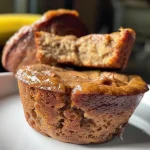 ['Close-up of golden brown protein banana muffins with a soft texture.', 'Side view of delicious protein banana muffins topped with chocolate chips.', 'Juicy protein banana muffins showcasing a moist interior and rich color.', 'Mouthwatering protein banana muffins arranged on a plate, highlighting their fluffy appearance.']