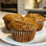 ['Close-up of a moist pumpkin protein muffin with a golden-brown exterior.', 'Side view of a delicious pumpkin protein muffin showcasing its soft texture.', 'Juicy pumpkin protein muffin featuring a rich, inviting color and toppings.', 'Detailed image of a pumpkin protein muffin highlighting the fluffy interior.']