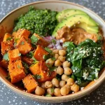 ['Close-up view of a vibrant Sweet Potato Quinoa Bowl drizzled with almond sauce, featuring colorful ingredients.', 'A delicious bowl filled with quinoa, sweet potato, chickpeas, and fresh spinach, topped with creamy almond sauce.', 'Side view of a healthy Sweet Potato Quinoa Bowl, showcasing layers of ingredients including avocado and hemp hearts.', 'Appetizing close-up of a Sweet Potato Quinoa Bowl with chickpeas, spinach, and a drizzle of almond butter sauce.']