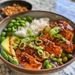 ['A vibrant Teriyaki Salmon Bowl featuring chunks of salmon, rice, green edamame, and sliced avocado.', 'Close-up view of a Teriyaki Salmon Bowl with colorful ingredients including salmon, rice, and garnishes.', 'A delicious Teriyaki Salmon Bowl showcasing salmon filets, rice, and fresh vegetables, displayed from the side.', 'Side view of a Teriyaki Salmon Bowl filled with juicy salmon chunks, rice, and topped with scallions and sesame seeds.']
