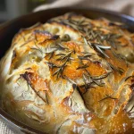 ['Close-up side view of a rustic Rosemary-Olive Sourdough Bread loaf with a golden crust.', 'Detailed view of sliced Rosemary-Olive Sourdough Bread showcasing olives and rosemary flecks.', 'Side angle of a freshly baked Rosemary-Olive Sourdough Bread loaf with a crispy crust.', 'Textured close-up of Rosemary-Olive Sourdough Bread revealing its airy crumb and toppings.']