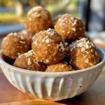 ['Close-up view of Pumpkin Protein Balls coated in shredded coconut.', 'Side angle of juicy Pumpkin Protein Balls on a wooden surface.', 'Detailed shot of several Pumpkin Protein Balls arranged attractively.', 'Textured surface of Pumpkin Protein Balls with a warm, autumn color scheme.']