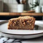 ['A close-up side view of a slice of moist vegan oat cake on a plate, showing its fluffy texture.', 'A beautifully presented piece of vegan oat cake, highlighting the oat flour and almond flour layers.', 'A delicious slice of vegan oat cake with visible cinnamon and a drizzle of syrup, captured in soft natural light.', 'A tantalizing side view of a moist vegan oat cake slice, showcasing its rich ingredients and healthy toppings.']