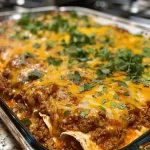 ['A close-up side view of a juicy Beef Enchilada Casserole topped with melted cheese.', 'A delicious plate of Beef Enchilada Casserole with layers of beef, cheese, and tortillas visible.', 'A mouthwatering Beef Enchilada Casserole showcasing the vibrant colors of beef, cheese, and toppings.', 'Side view of a Beef Enchilada Casserole, with a rich filling and gooey cheese melty on top.']