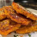 ['Juicy butternut squash fritters arranged on a plate with a golden-brown crust.', 'Close-up of crispy butternut squash fritters garnished with fresh thyme.', 'Side view of delicious butternut squash fritters showcasing their texture and color.', 'Plated butternut squash fritters with melted cheese visible in the strands.']