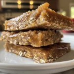 ['A close-up side view of a caramel apple protein bar with a glossy caramel layer and visible apple chunks.', 'A delicious-looking caramel apple protein bar, showcasing its chewy texture and caramel drizzle.', 'An appetizing caramel apple protein bar displayed on a neutral background, highlighting its ingredients and texture.', 'A detailed view of a caramel apple protein bar, featuring chunks of apples and a rich caramel topping.']